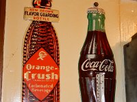 412 - COCA COLA BOTTLE THERMOMETER, 16" TALL; 413 - ORANGE CRUSH FIGURAL BOTTLE TIN SIGN, 18" TALL